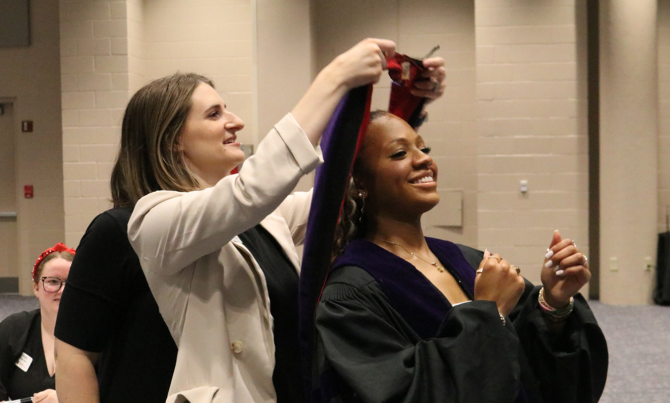 Director of Development Gabby Dukes helps Natalya Moody get ready for graduation.